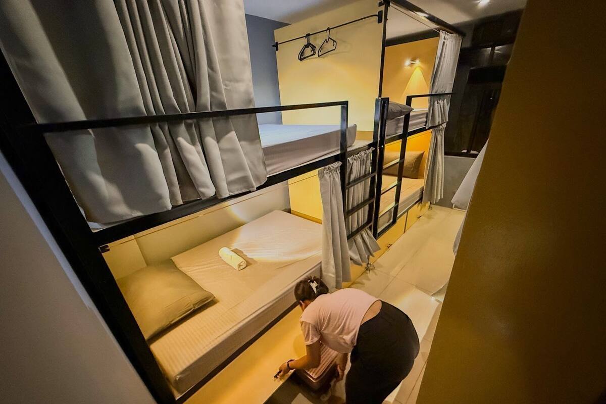 A bunk bed room with a person organizing items on the lower bunk.