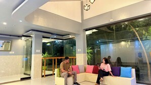 En moderne lobby med glasvæg, siddeområde og loft med geometriske lamper.