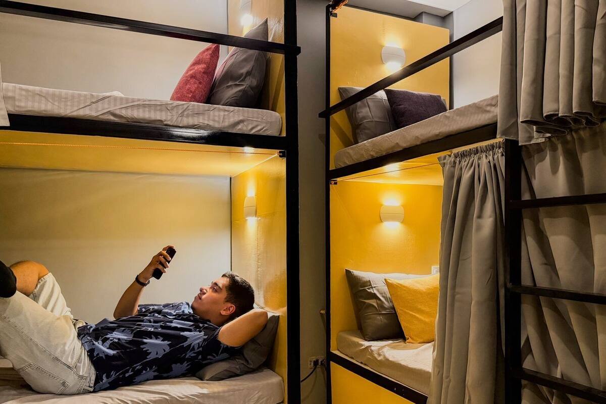 A bunk bed room with two beds, each with pillows and a headboard.