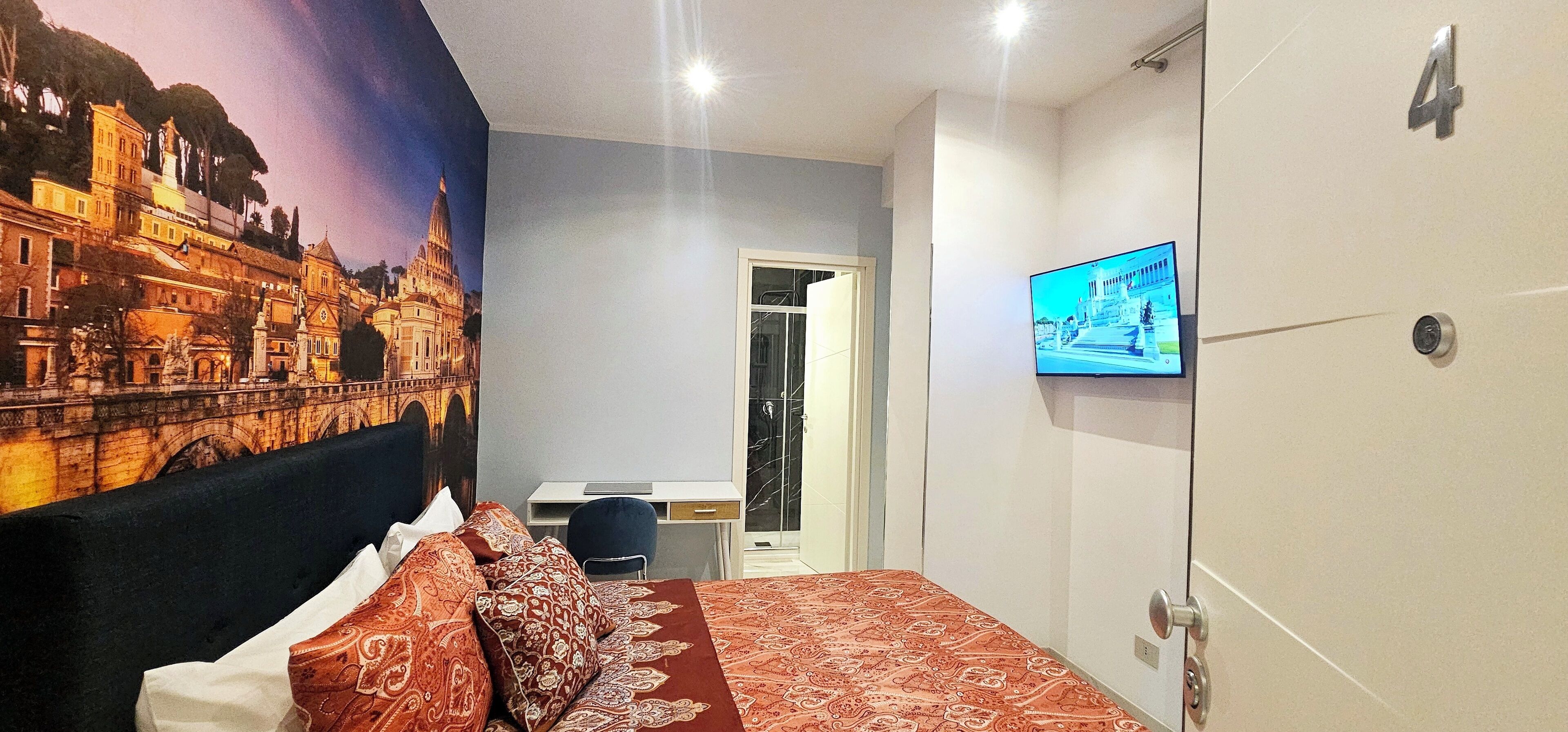 Ett hotellrum med en säng, ett skrivbord, en tv och en dörr.