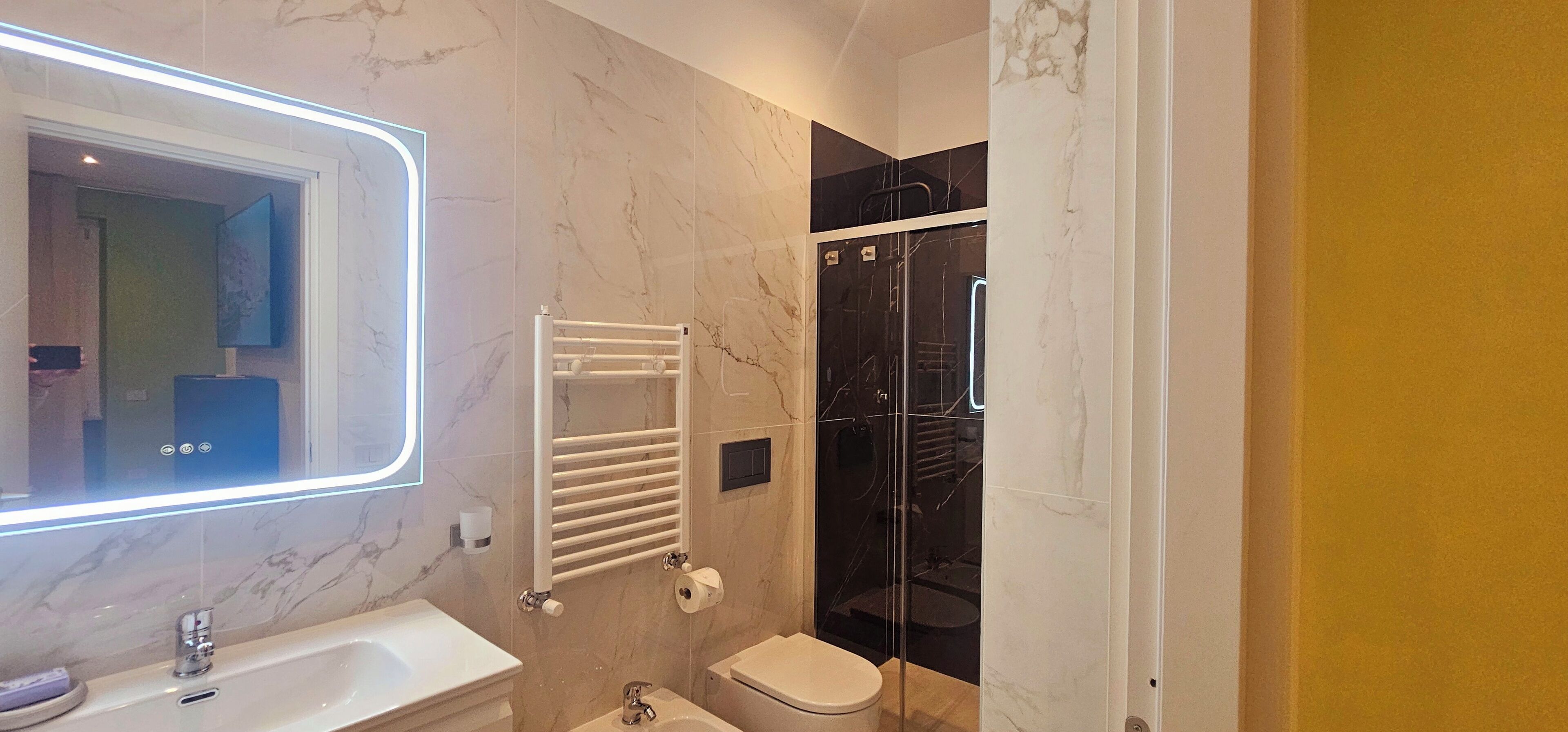 A modern bathroom with a marble sink, a glass-enclosed shower, and a white toilet.