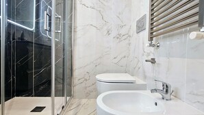 Een moderne badkamer met een douchecabine van glas, een wit toilet en een wastafel met een chromen kraan.