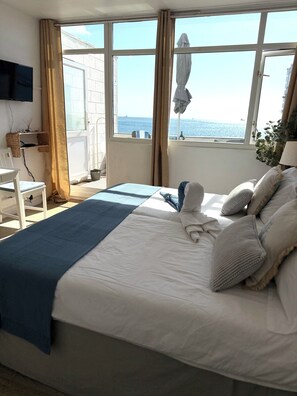 A hotel room with a bed, a desk, and a view of the sea. - Beautiful Beachfront Studio Apartment with Sea View Balcony in Gibraltar (Gibraltar)