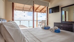A hotel room with a bed, a desk, a chair, and a balcony with a view. - Sunset Vista Exclusive villa (Zakynthos)