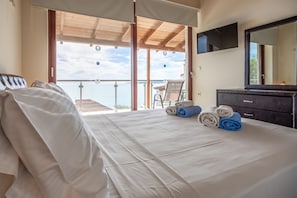 A hotel room with a bed, a desk, a chair, and a balcony with a view.