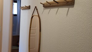 Un pasillo con un perchero de madera, un espejo y una puerta que da a otra habitación.