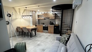 Een knus woongedeelte met een kitchenette, een eethoek en een zithoek met een bank en voetenbankje.