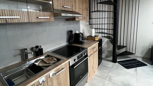 Een moderne keuken met houten kastjes, een RVS-spoelbak en een zwart fornuis.
