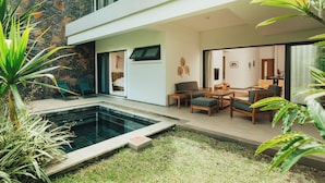 A modern house with a swimming pool, outdoor seating, and a stone wall. - Lakaz Filao - Premium Apt - private pool & garden (Grande Riviere Noire)