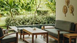 A cozy outdoor seating area with wooden furniture and a view of lush greenery. - Lakaz Filao - Premium Apt - private pool & garden (Grande Riviere Noire)