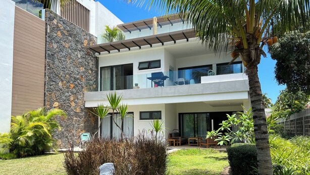 A modern two-story house with a stone facade, large windows, and a covered outdoor seating area. - Lakaz Filao - Premium Apt - private pool & garden (Grande Riviere Noire)