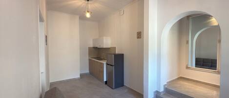 A modern apartment with a kitchenette, a sofa, and a staircase leading to an upper level.