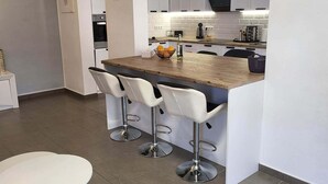 A modern kitchen with a central island, white bar stools, and a round dining table.