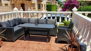 A rooftop terrace with a sofa set, potted plants, and a decorative lamp.