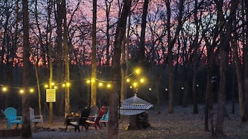A forested area with string lights, a gazebo, and outdoor seating.