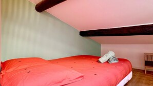 A small, cozy room with a sloped ceiling, a single bed with red bedding, and a small wooden chair. - Le Studio des Tilleuls, Air-Conditioned & Real Bed (Nîmes)
