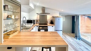 A modern kitchen with wooden flooring, a built-in microwave, and a stainless steel range hood. - La Tropézienne, charm and comfort in the Gard. (Saint-Geniès-de-Malgoirès)