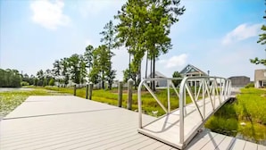 Eine Holzterrasse mit Metallgeländer, einem kleinen Wasserspiegel und viel Grün.