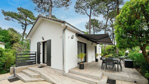 A modern house with a covered patio, outdoor seating, and a small garden.