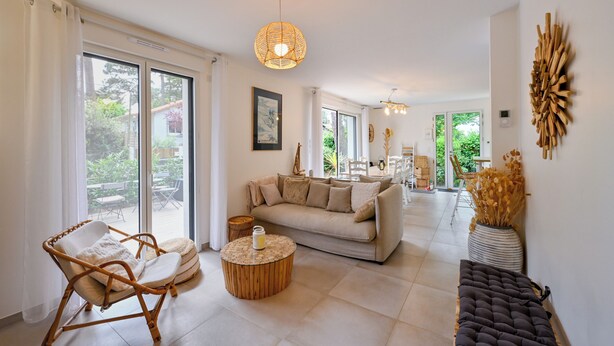 A spacious living area with a sofa, a wicker chair, a round coffee table, and a bench.