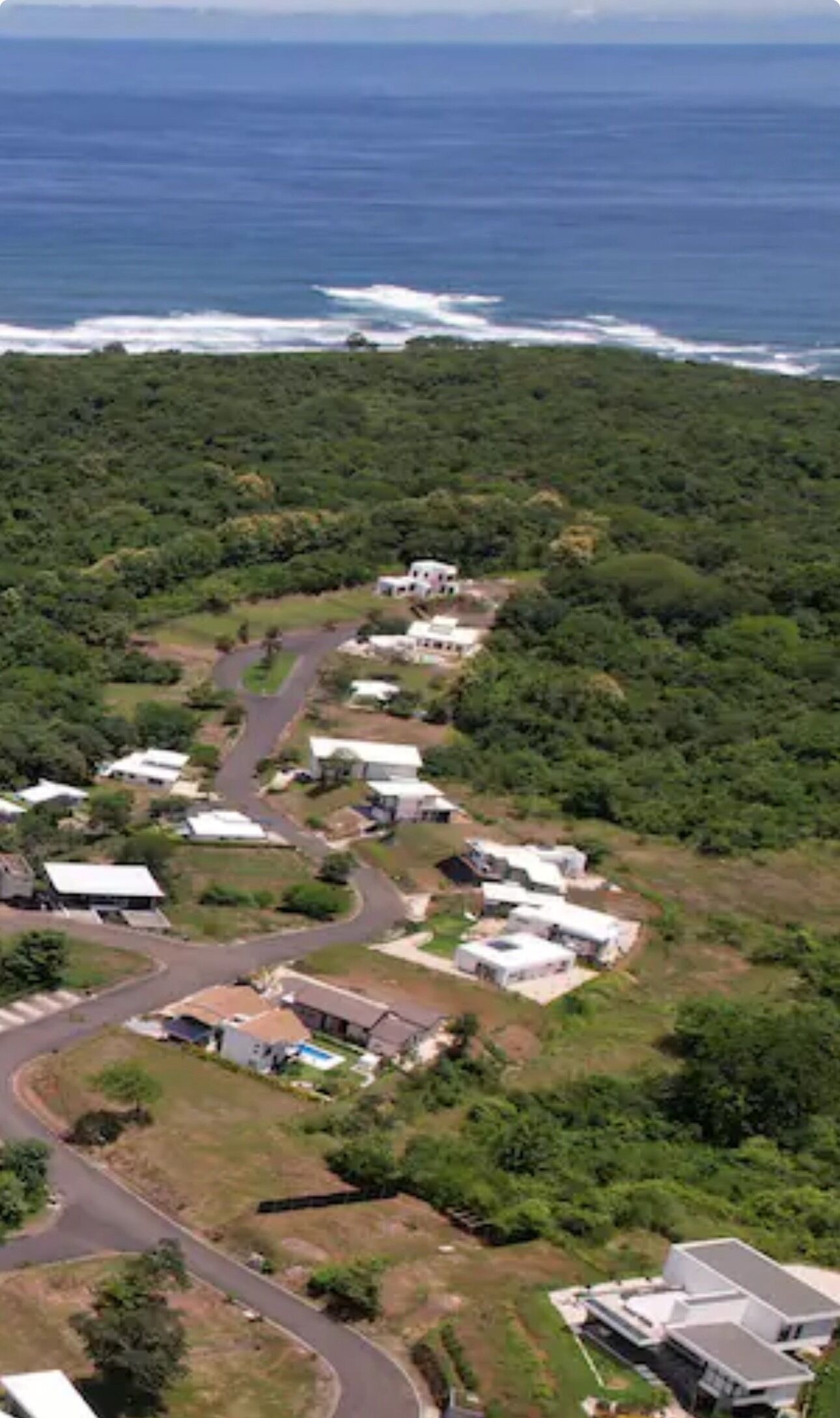 Vista aérea de una zona costera con una carretera que conduce a una hilera de casas.