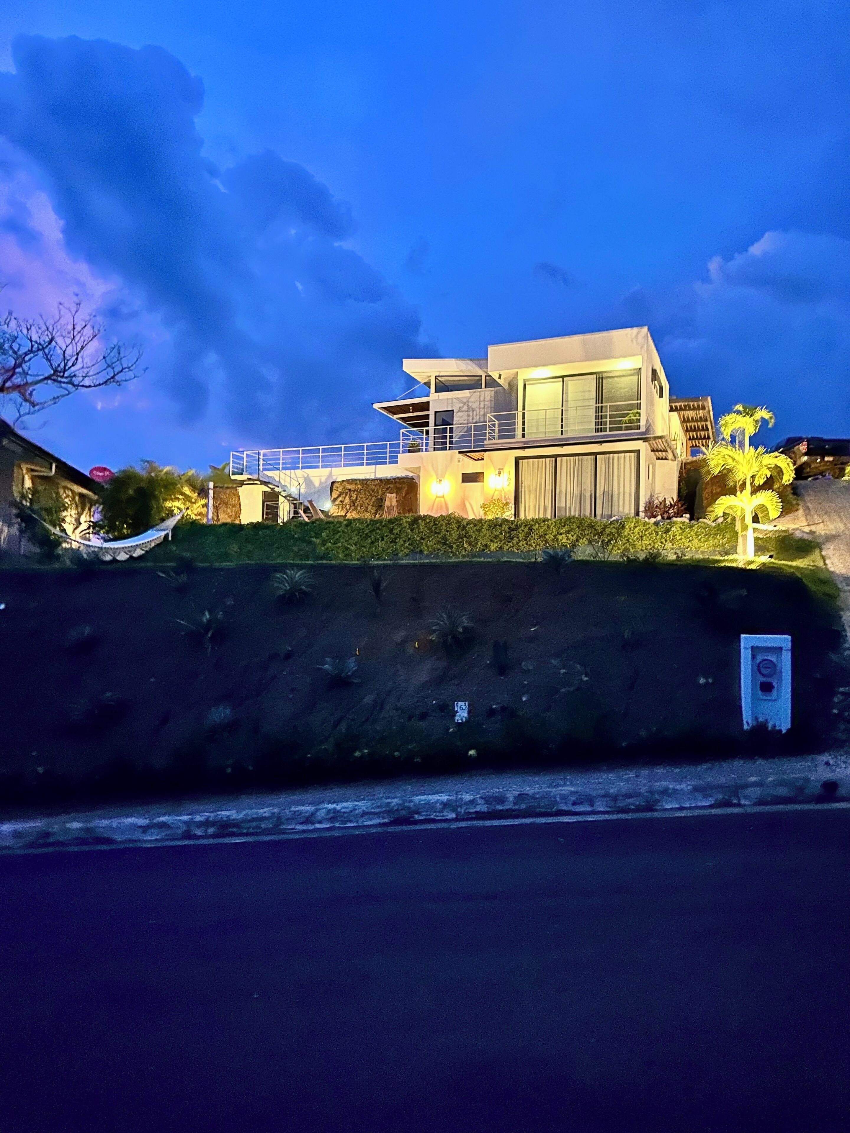 Ein modernes, zweistöckiges Haus mit flachem Dach, gro ßen Fenstern und einem Balkon.