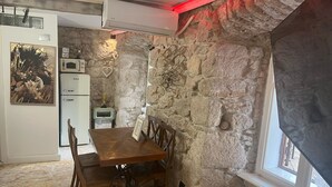 A rustic kitchen with stone walls, a wooden dining table, and a vintage radio. - Dora (Bakar)