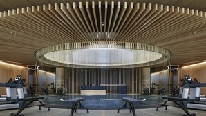 Ein modernes Fitnessstudio mit einem zentralen, kreisförmigen Design, Spiegelwänden und Trainingsgeräten.