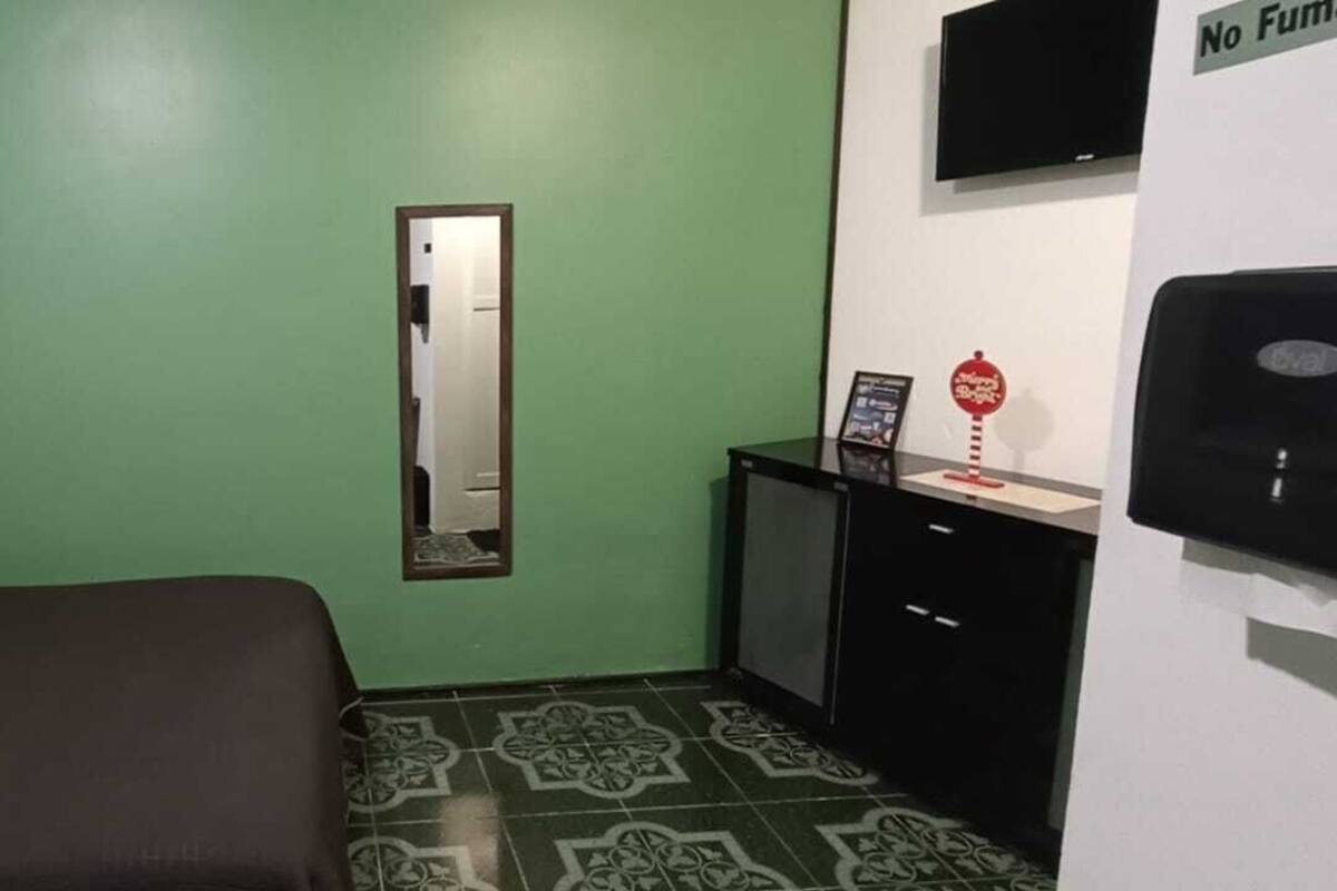 Una habitación con una cama, una mesita de noche con un espejo y un televisor en la pared.
