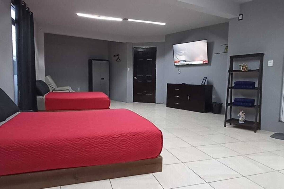 Una habitación con dos camas, televisión, armario y escritorio.