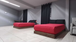 Une chambre avec deux lits, une chaise, une petite table et une étagère fixée au mur.