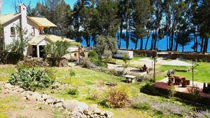 A house with a stone foundation, a wooden deck, and a view of the sea.