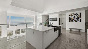 A modern kitchen with a large island, a view of the city, and a contemporary art piece on the wall. - 5000sf Luxury 5BR, Hot Tub, Panoramic Views, Games, Fire Pit (Spring Valley)