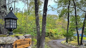 A wooden sign welcoming visitors to The Library Inn, set against a backdrop of trees and a stone wall. - The Vibrary Inn, a Fantasy Minnewaska Escape. Minutes from Hikes and Waterfalls. (Kerhonkson)