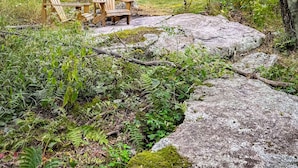 A forested area with two wooden Adirondack chairs, a hammock, and a house in the background. - The Vibrary Inn, a Fantasy Minnewaska Escape. Minutes from Hikes and Waterfalls. (Kerhonkson)