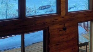 A cabin with large windows offering a view of a snowy forest. - Stunning Custom Made Log Home- on 30 acres (Grand Forks)