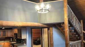 A spacious kitchen with wooden beams, a dining area, and a staircase. - Stunning Custom Made Log Home- on 30 acres (Grand Forks)