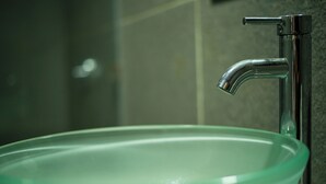Une salle de bain avec un lavabo en verre vert et un robinet chromé.
