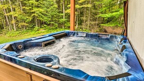 Un jacuzzi con terraza de madera y vista a un bosque.