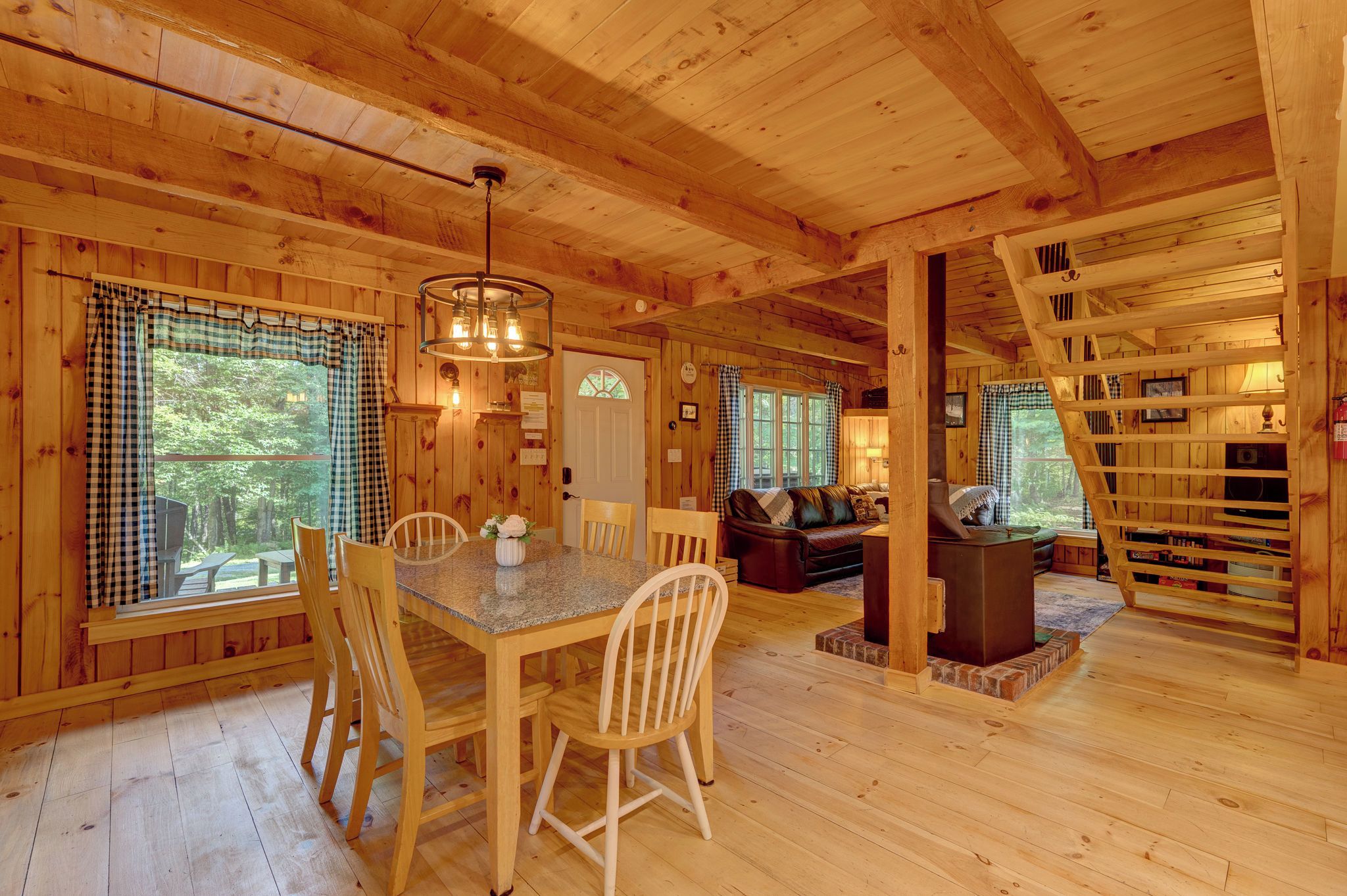 Ein Interieur einer Holzhütte mit Essbereich, einer Couch und einem Kamin.