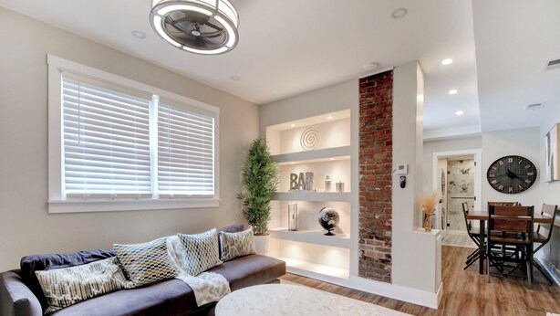 A modern living room with a dark brown sofa, white round coffee table, and a brick accent wall.