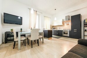 A modern kitchen with a flat-screen TV, dining table, chairs, and a sofa. - [Historic Center, steps from Rome] Cozy Apartment with Suite (Monterotondo)