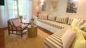 Een woonkamer met een gestreept sofa, een houten stoel, een klein rond tafeltje en een decoratieve vaas.