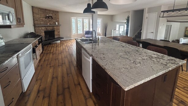 A modern kitchen with a large island, wooden flooring, and pendant lighting. - Cozy Calgary Stampede Sanctuary Home (Calgary)
