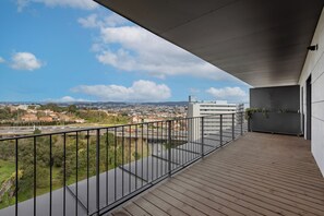 A balcony with a view of a cityscape, a wooden floor, and a metal railing. - Antas Green Executive (Porto)