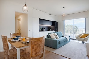 A modern living space with a dining area, a sofa, and a balcony with a view. - Antas Green Executive (Porto)