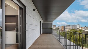 Un balcon doté d’un plancher en bois, d’une rambarde en métal et offrant une vue sur la ville.
