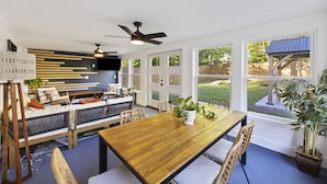 A spacious dining area with a wooden table and chairs, a ceiling fan, and large windows offering a view of the backyard. - Tailgaters paradise, grill, game room, sunroom-large backyard! (Columbia)