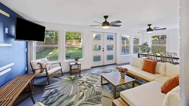 A spacious living area with a large window, a ceiling fan, and a flat-screen TV mounted on the wall. - Tailgaters paradise, grill, game room, sunroom-large backyard! (Columbia)