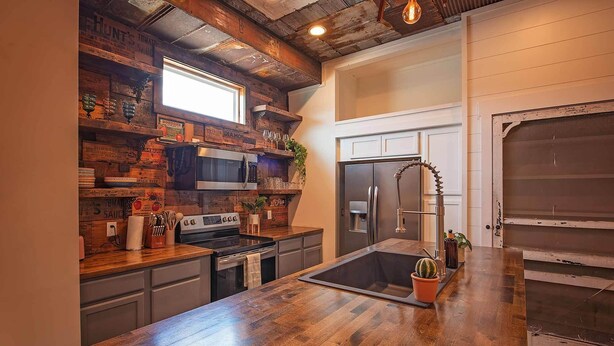 Una cocina con encimera de madera, electrodomésticos de acero inoxidable y un amplio ventanal.